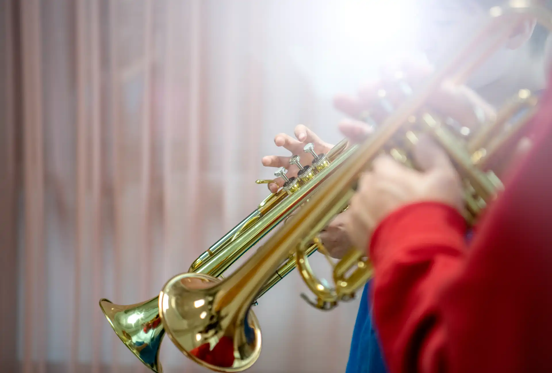 Foto på två elever som spelar på var sin trumpet. Solen lyser genom fönstret